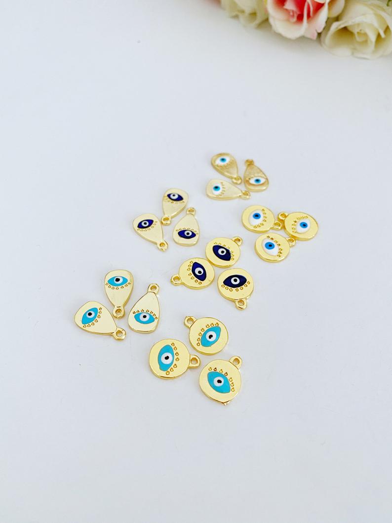 Five gold evil eye charms in round and oval shapes, featuring blue, white, and turquoise colors, ideal for DIY jewelry making.