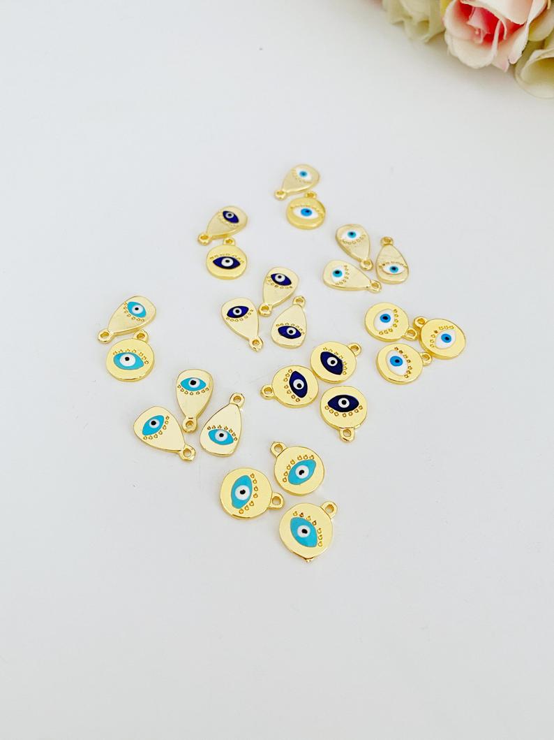 Five gold evil eye charms in round and oval shapes, featuring blue, white, and turquoise colors, ideal for DIY jewelry making.