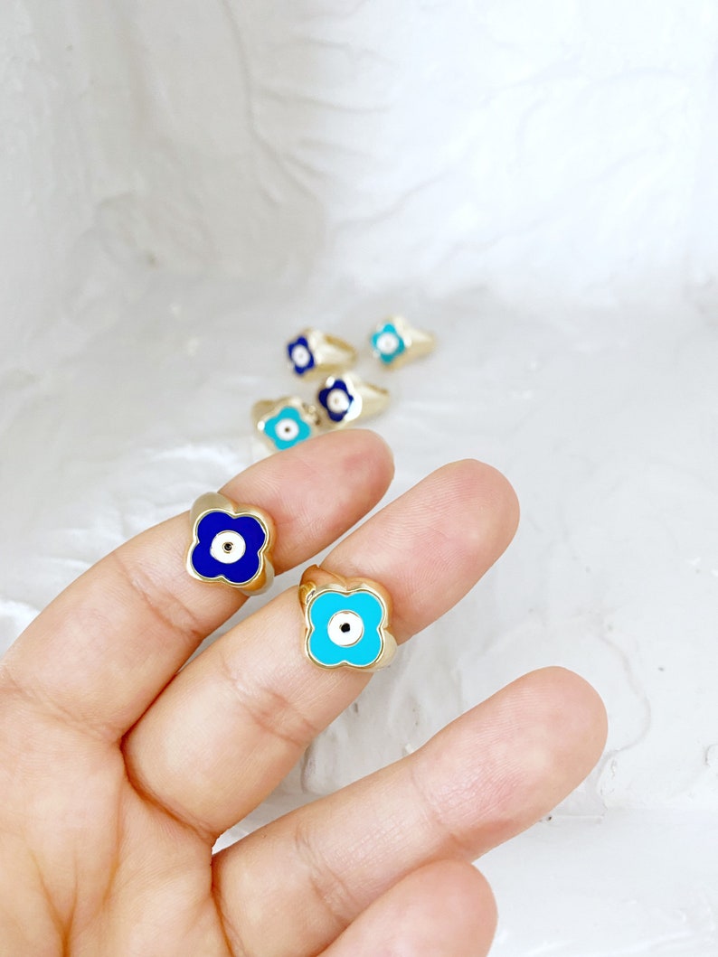 Gold Evil Eye Ring featuring an adjustable band and a four-leaf clover charm in navy blue and turquoise colors.