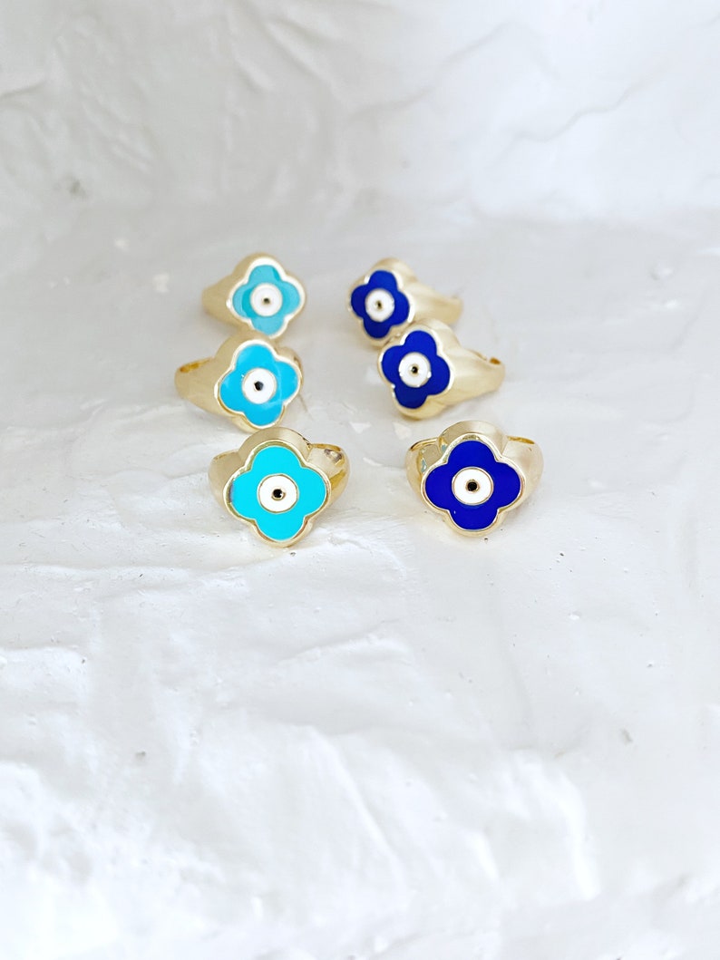 Gold Evil Eye Ring featuring an adjustable band and a four-leaf clover charm in navy blue and turquoise colors.