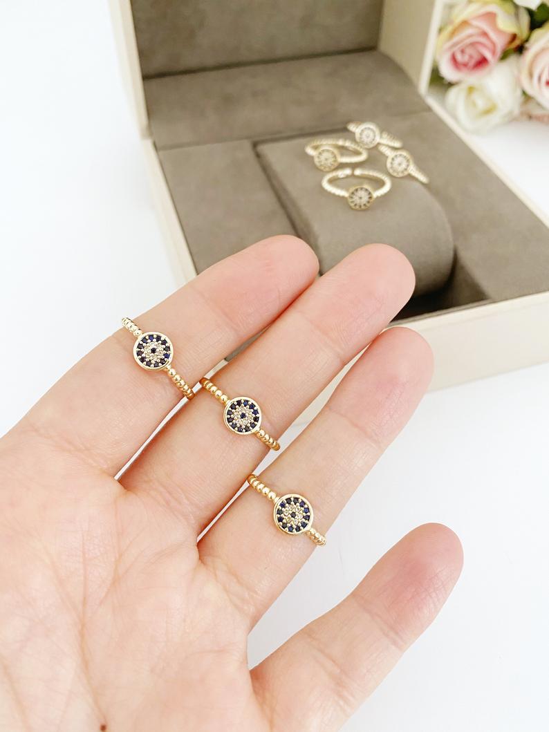 A delicate gold evil eye ring featuring a zircon charm, adjustable for all sizes, perfect for everyday wear.