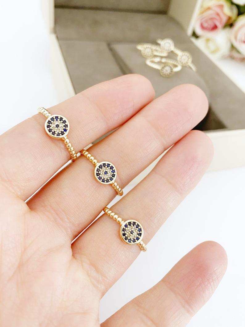 A delicate gold evil eye ring featuring a zircon charm, adjustable for all sizes, perfect for everyday wear.