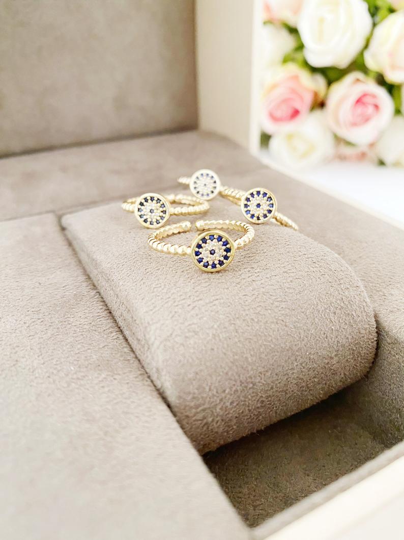 A delicate gold evil eye ring featuring a zircon charm, adjustable for all sizes, perfect for everyday wear.