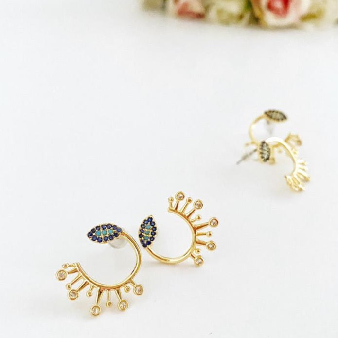 A pair of gold evil eye stud earrings featuring sparkling cubic zirconia paving, symbolizing protection and style.