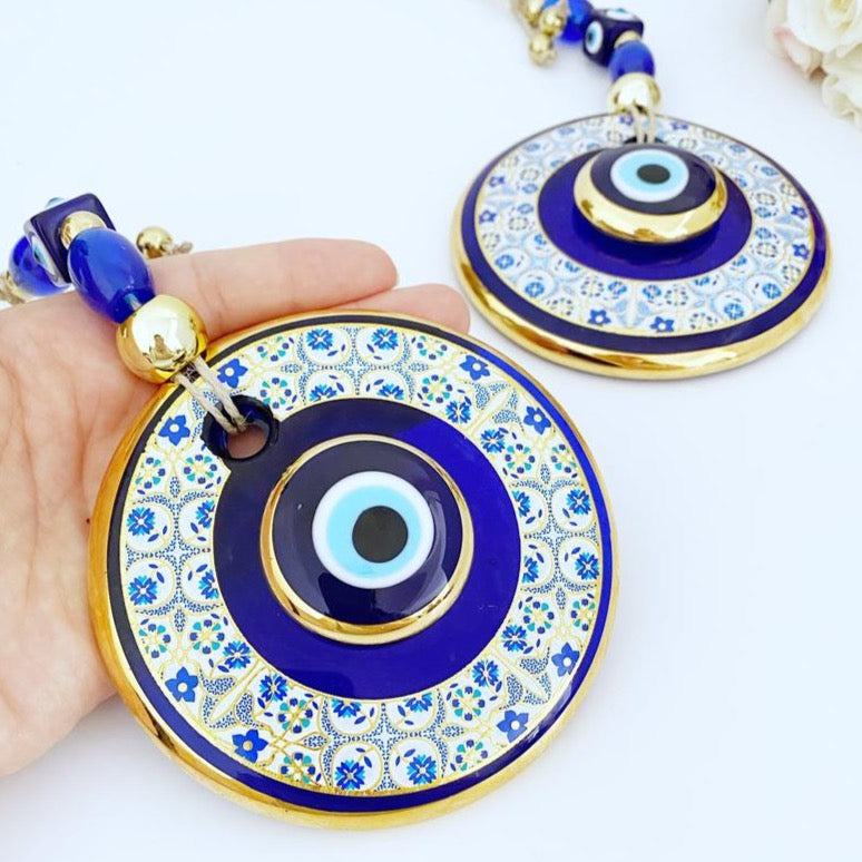 Gold Evil Eye Wall Hanging featuring a white patterned design, handmade with intricate details, symbolizing protection and good fortune.