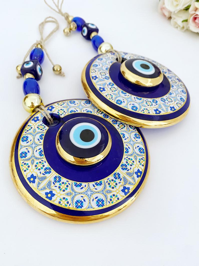 Gold Evil Eye Wall Hanging featuring a white patterned design, handmade with intricate details, symbolizing protection and good fortune.