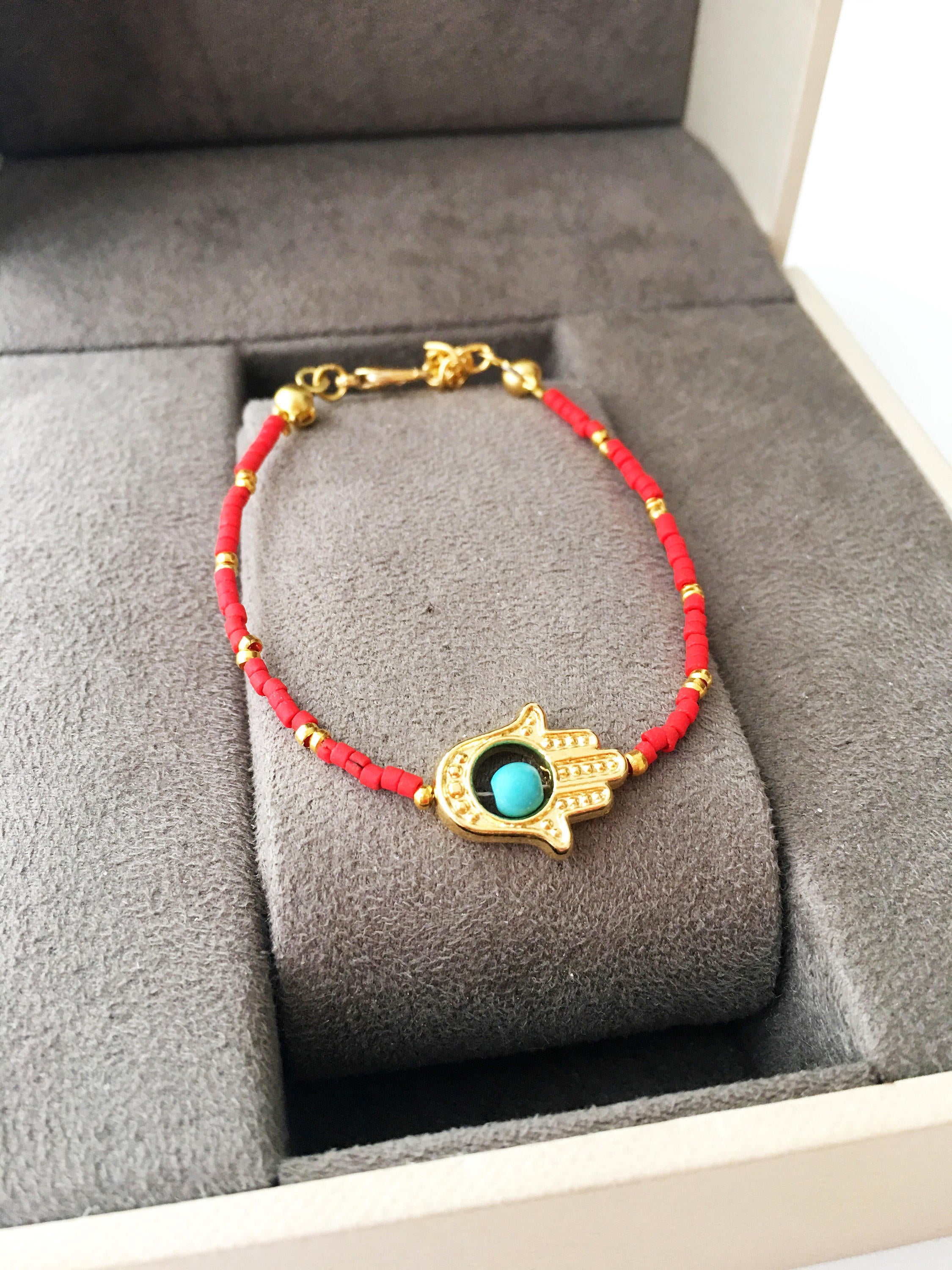 Gold Hamsa Hand Bracelet featuring colorful seed beads and a turquoise bead design, symbolizing luck and protection.