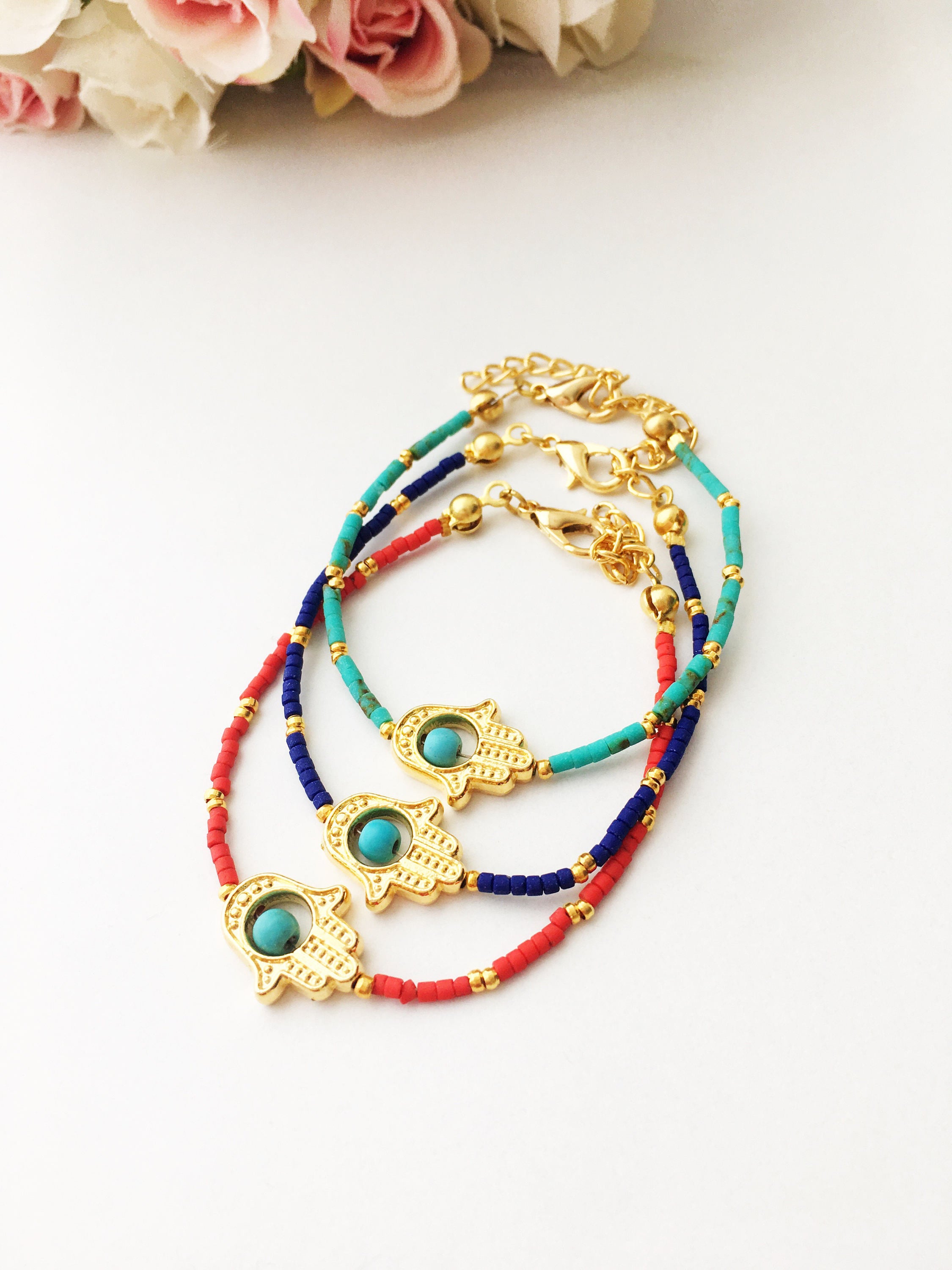 Gold Hamsa Hand Bracelet featuring colorful seed beads and a turquoise bead design, symbolizing luck and protection.