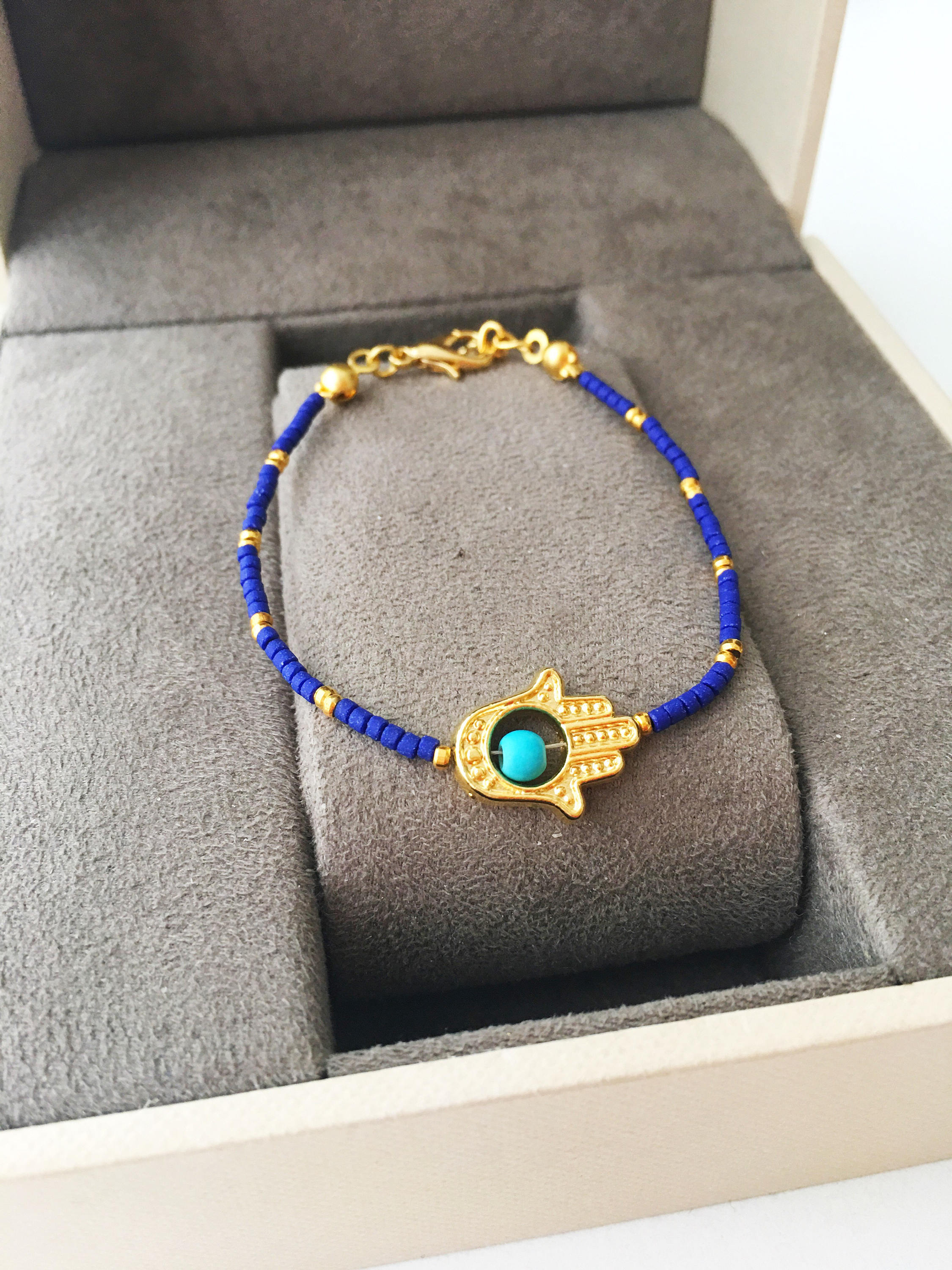 Gold Hamsa Hand Bracelet featuring colorful seed beads and a turquoise bead design, symbolizing luck and protection.