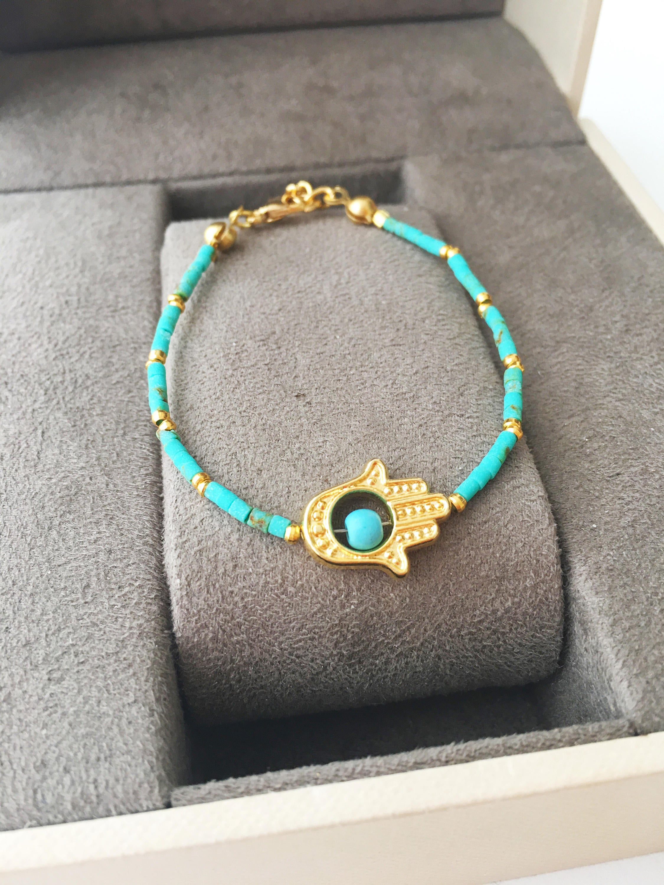 Gold Hamsa Hand Bracelet featuring colorful seed beads and a turquoise bead design, symbolizing luck and protection.