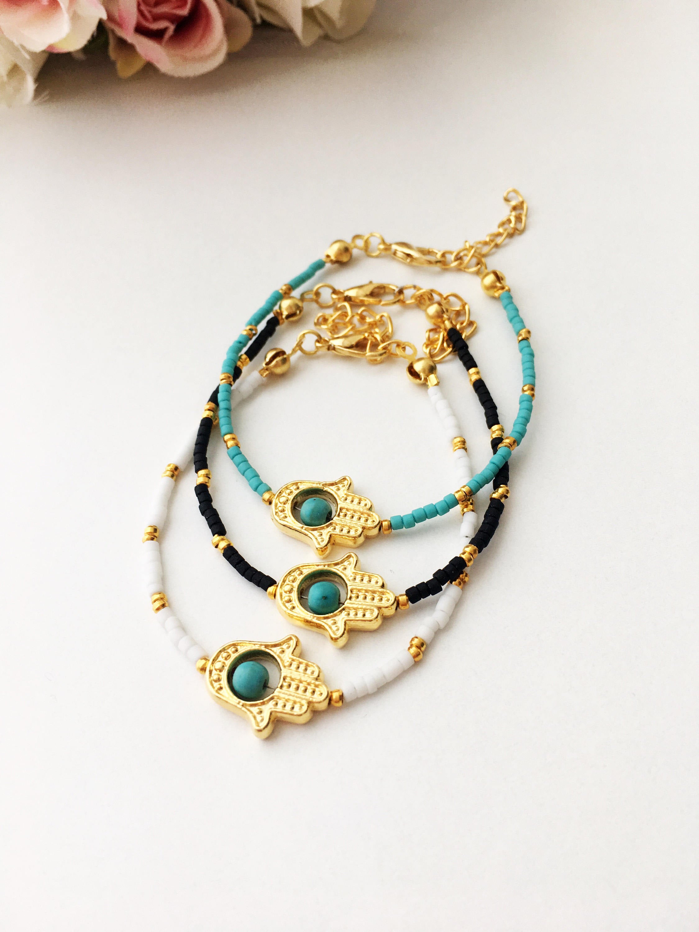 Gold Hamsa Hand Bracelet featuring colorful seed beads and a turquoise bead design, symbolizing luck and protection.