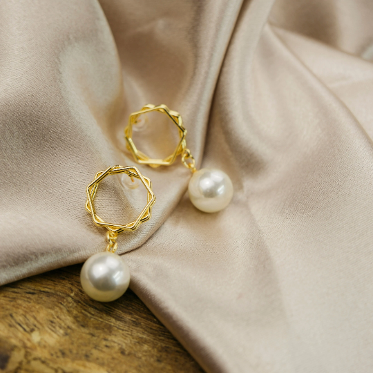 Gold hexagon earrings featuring a large white freshwater pearl, elegantly designed for a modern look.