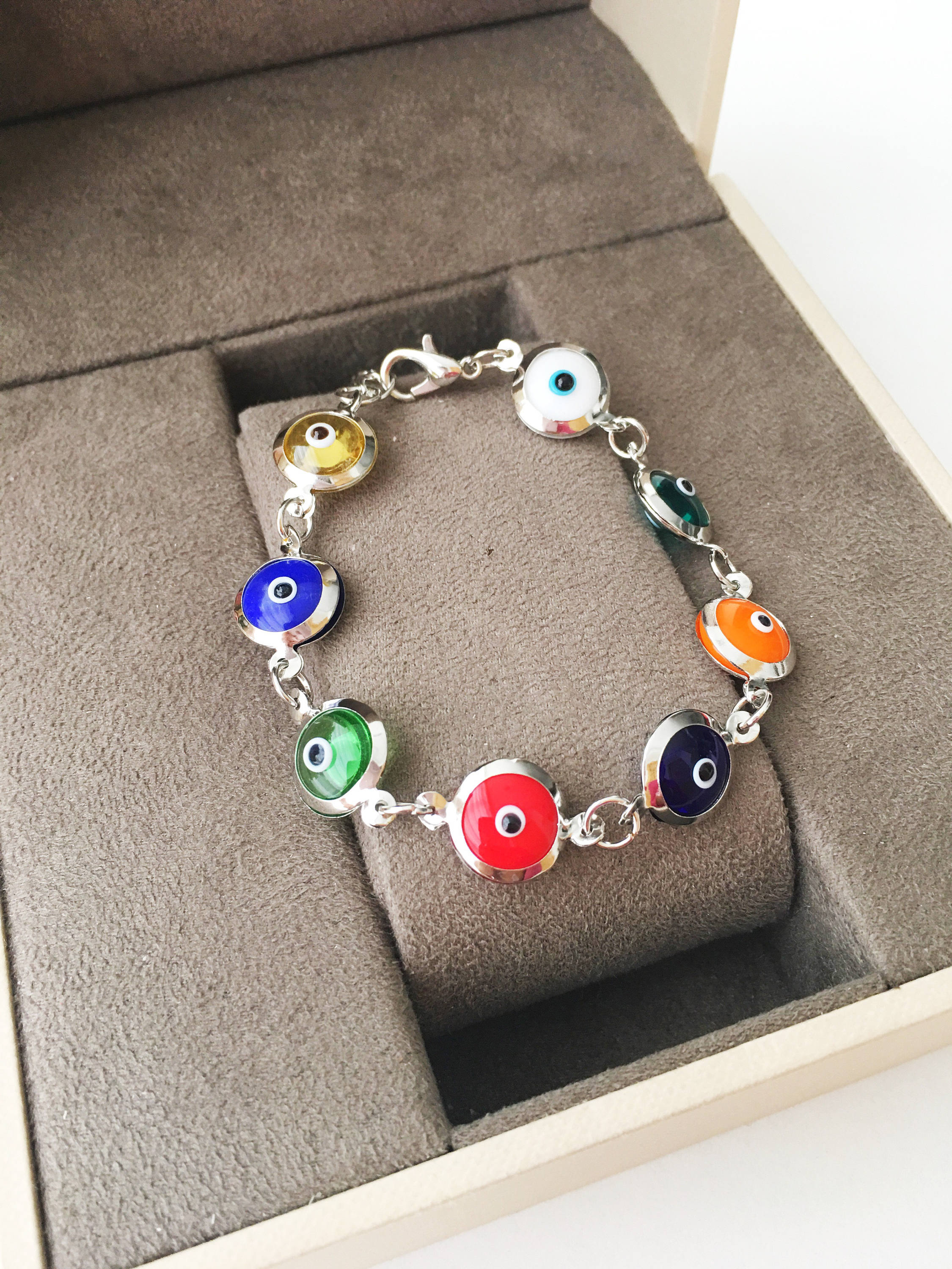 A colorful Gold Link Chain Bracelet featuring rainbow evil eye beads and a stainless steel chain, showcasing vibrant 12mm glass beads.
