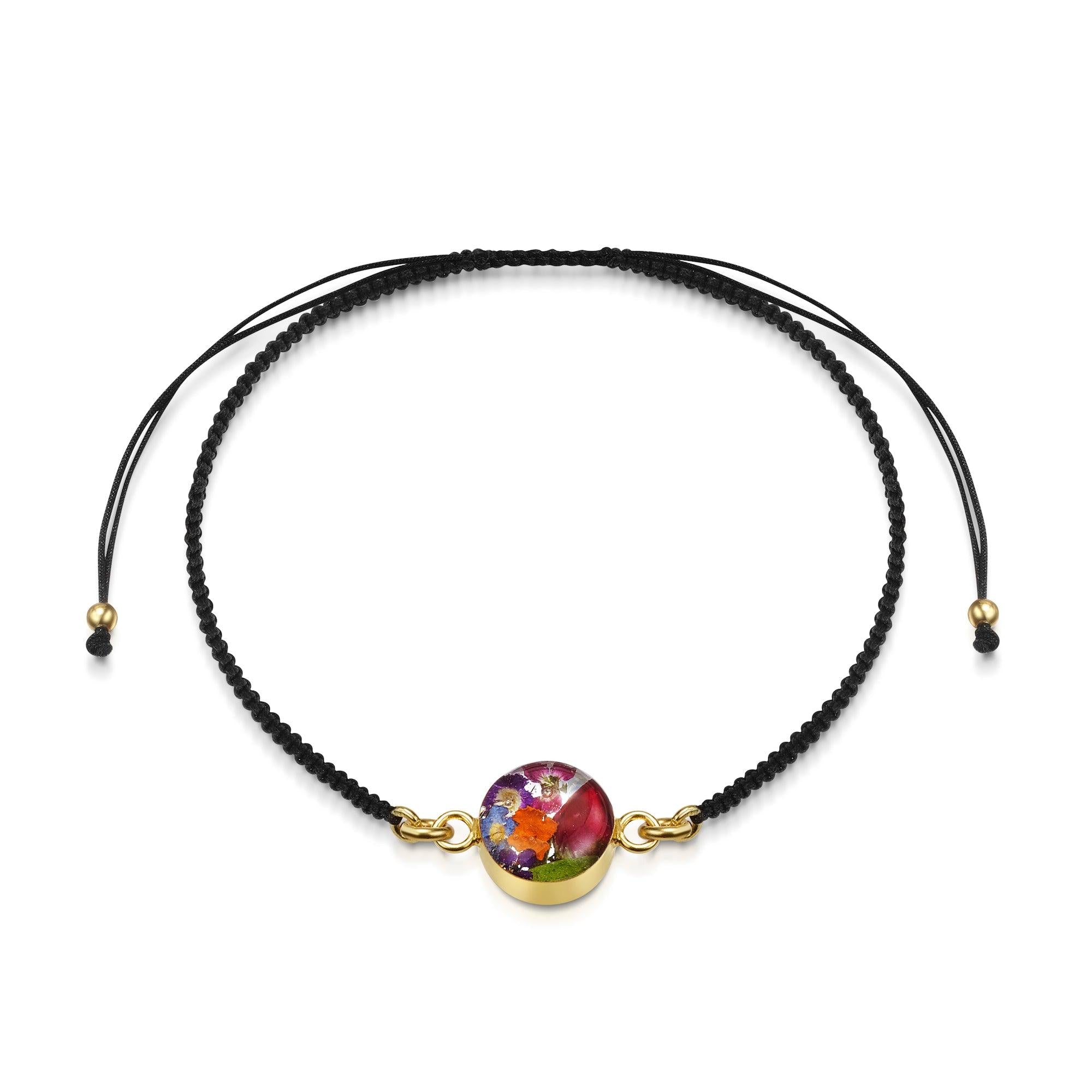 Gold plated black woven bracelet featuring a mixed flower charm, showcasing intricate design and elegant style.
