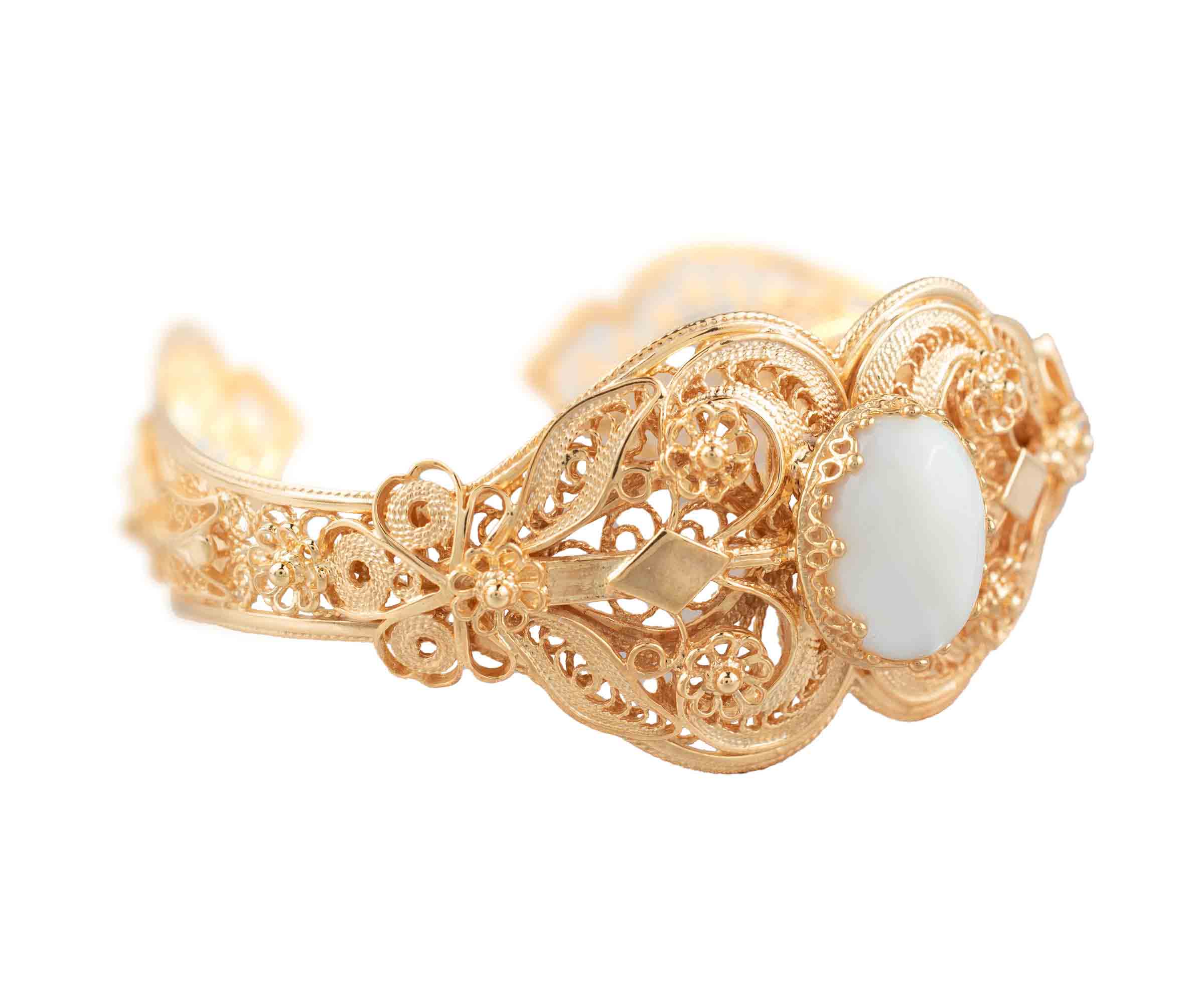 Gold plated sterling silver cuff bracelet with intricate filigree art and a mother of pearl gemstone, elegantly displayed in a velvet pouch.