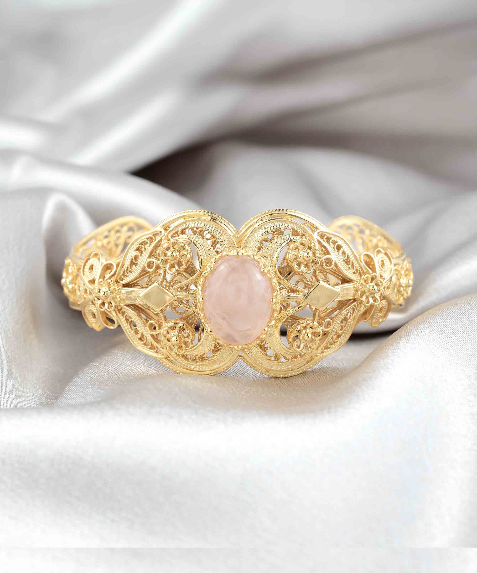 Elegant gold plated sterling silver cuff bracelet featuring intricate filigree art and a beautiful rose quartz gemstone.