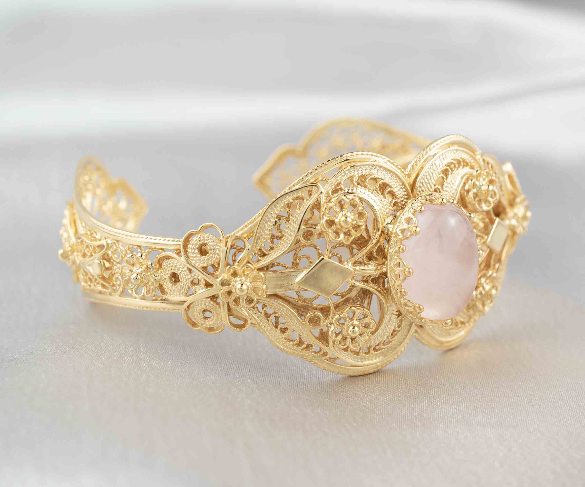 Elegant gold plated sterling silver cuff bracelet featuring intricate filigree art and a beautiful rose quartz gemstone.