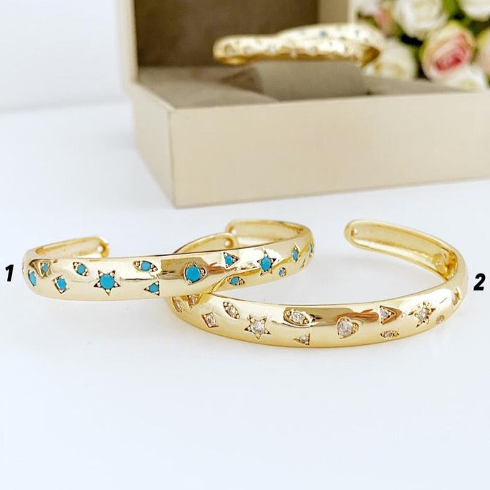 Gold wide bangle bracelet featuring a star charm and turquoise beads, showcasing its adjustable design and elegant craftsmanship.