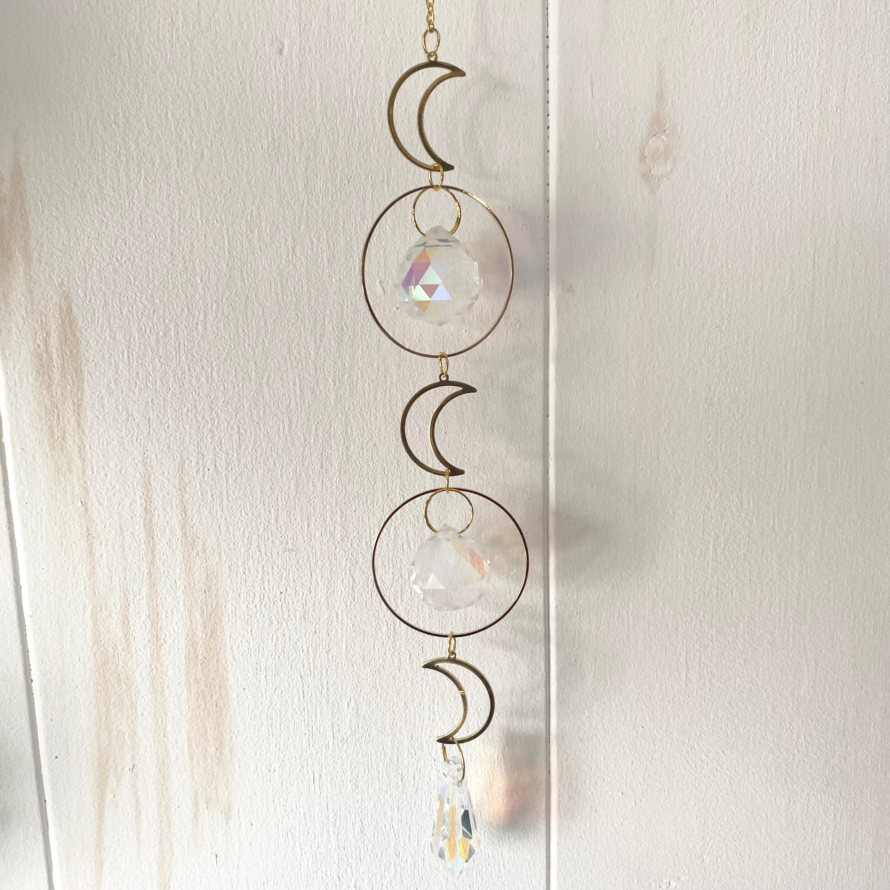 A beautiful Grand Rising Sun Catcher hanging in sunlight, creating vibrant rainbows.