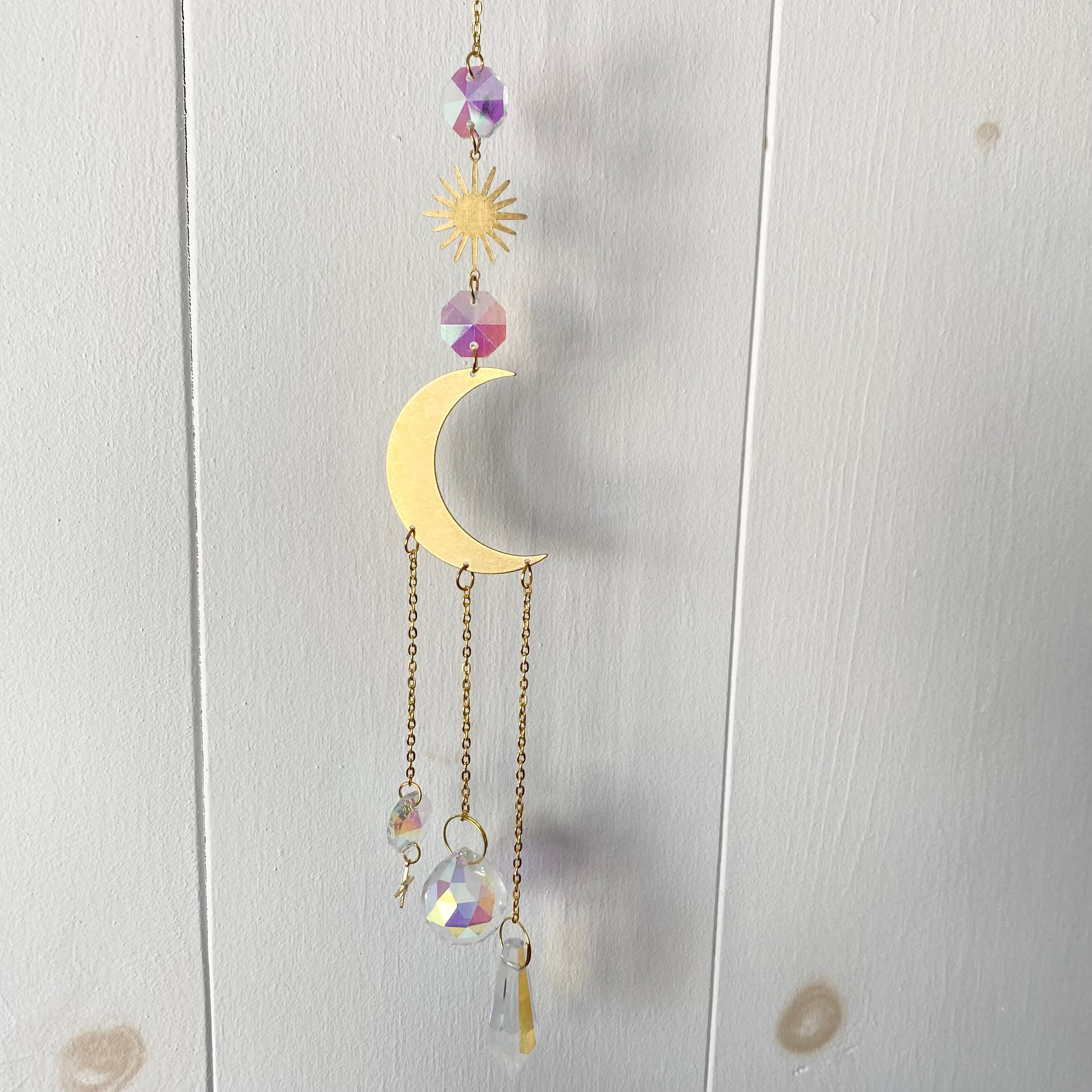 A beautiful Grand Rising Sun Catcher hanging in sunlight, creating vibrant rainbows.