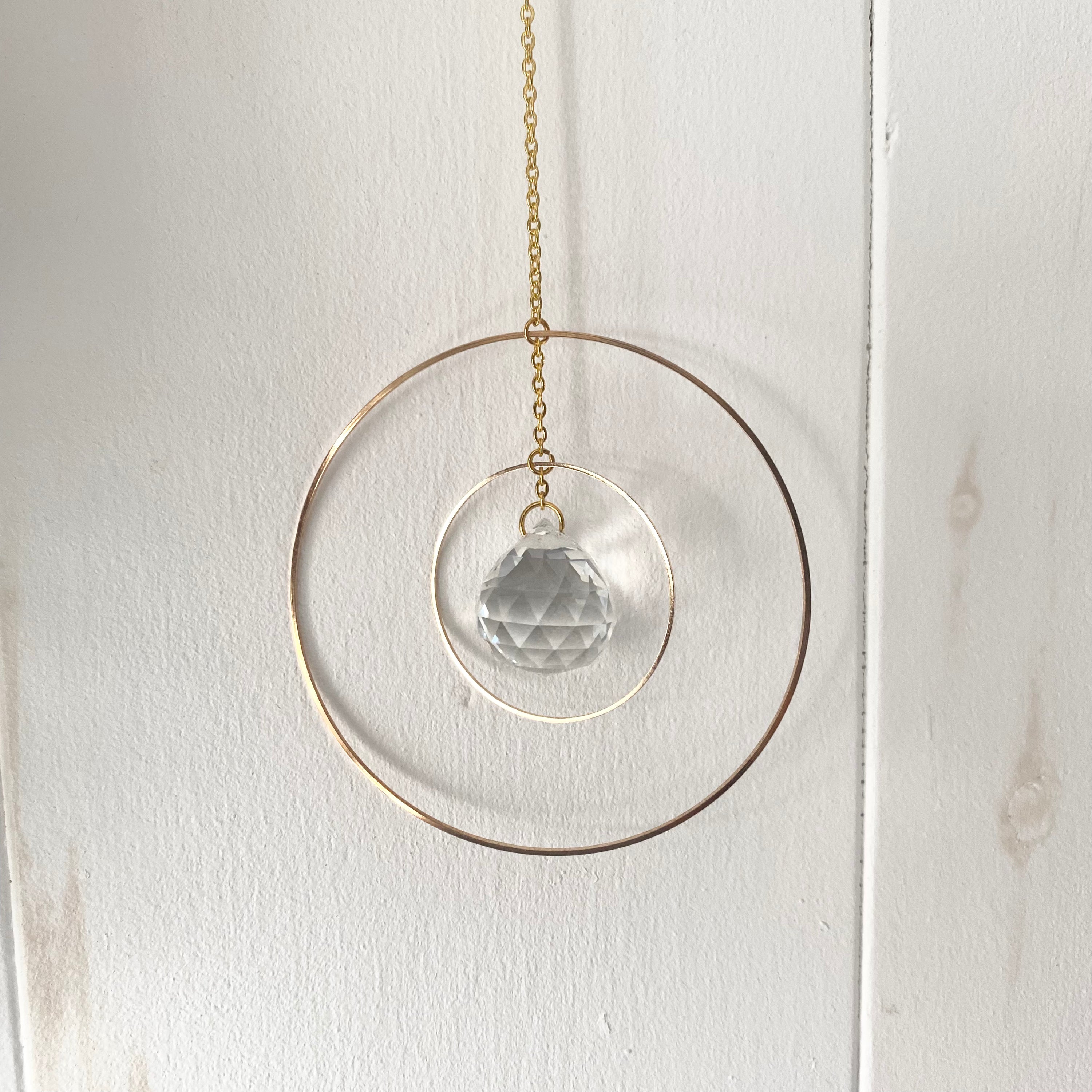 A beautiful Grand Rising Sun Catcher hanging in sunlight, creating vibrant rainbows.