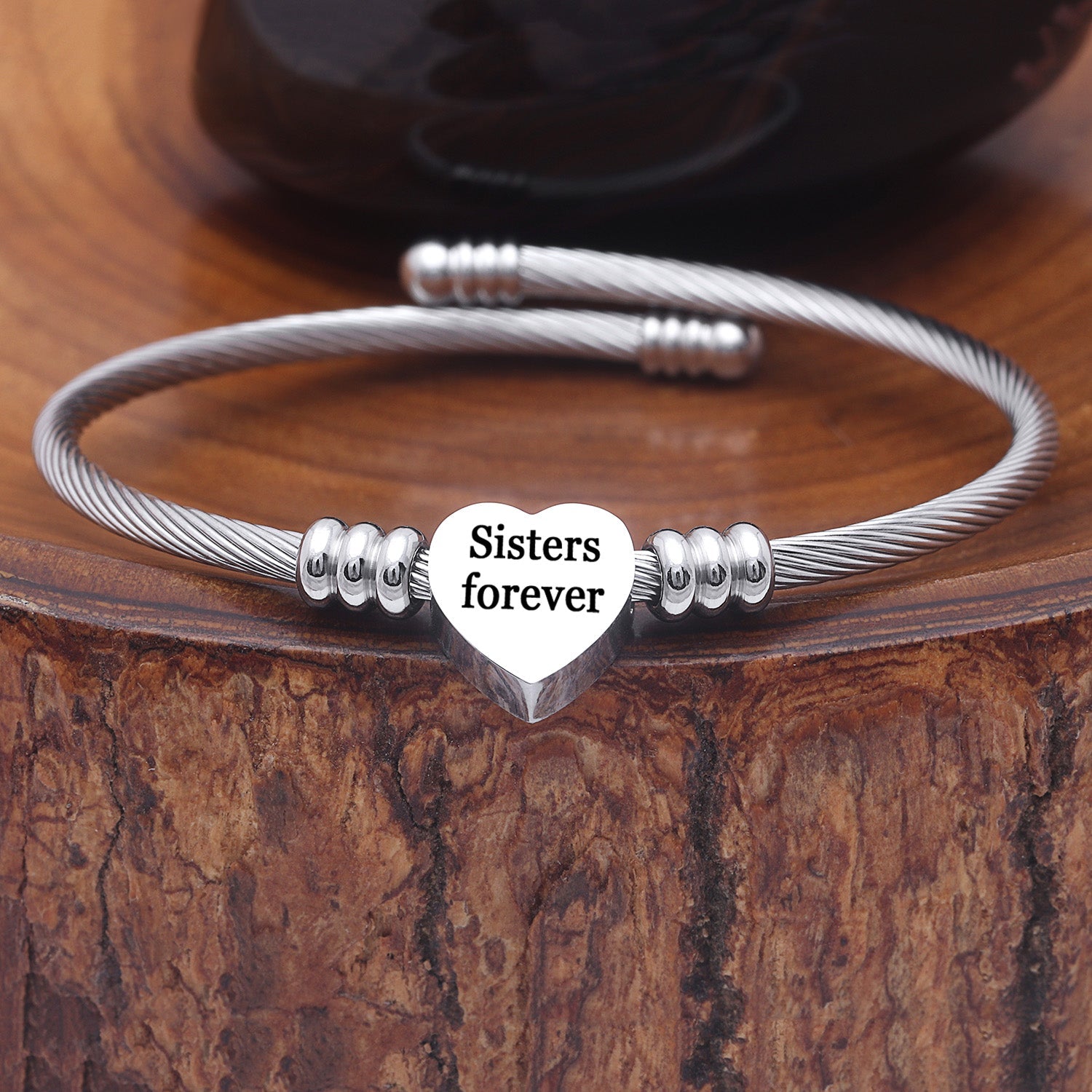A beautiful 'Sisters Forever' charm bangle made of solid stainless steel featuring a heart initial charm, elegantly polished for a shiny finish.