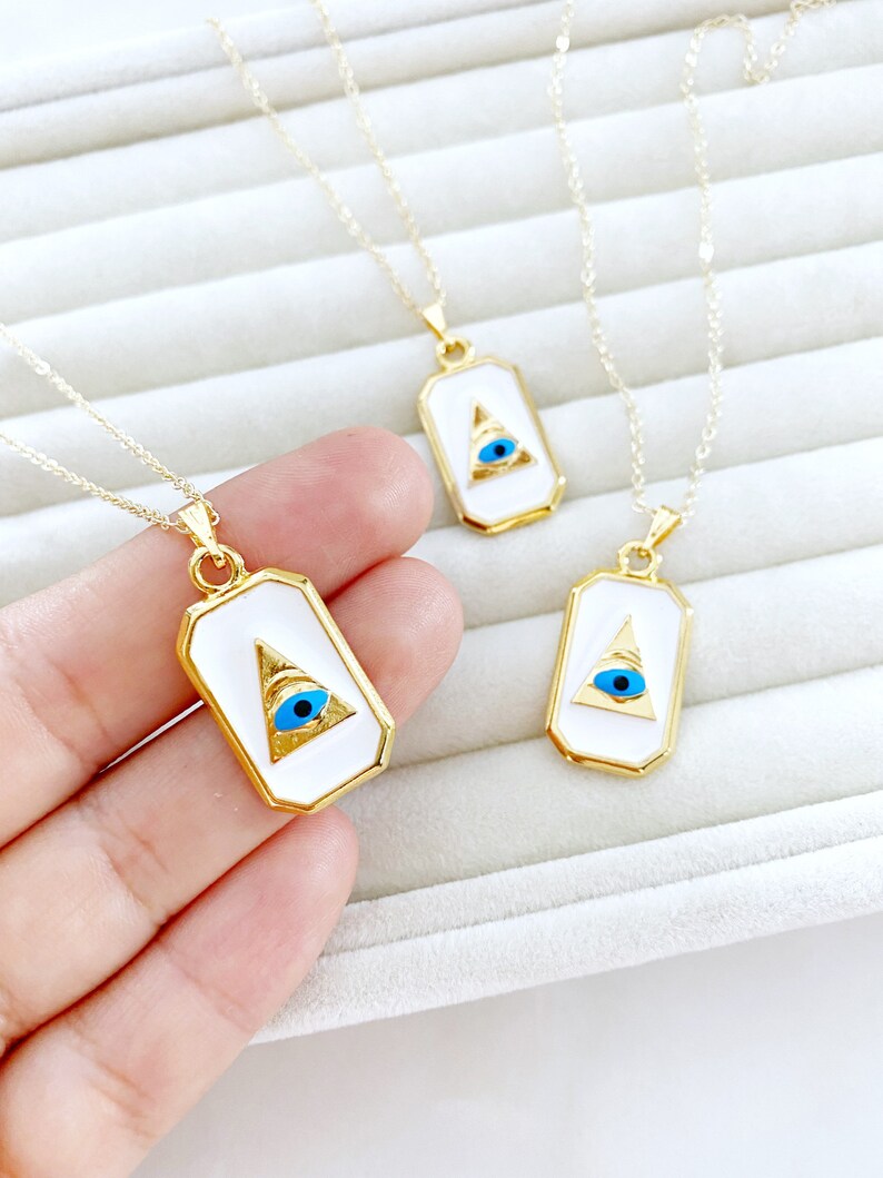 Grecee Evil Eye Necklace featuring a white enamel pendant on a gold chain, symbolizing protection and style.