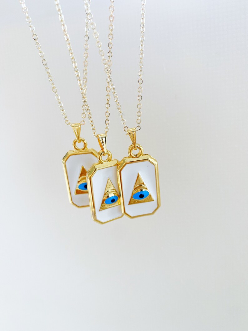Grecee Evil Eye Necklace featuring a white enamel pendant on a gold chain, symbolizing protection and style.