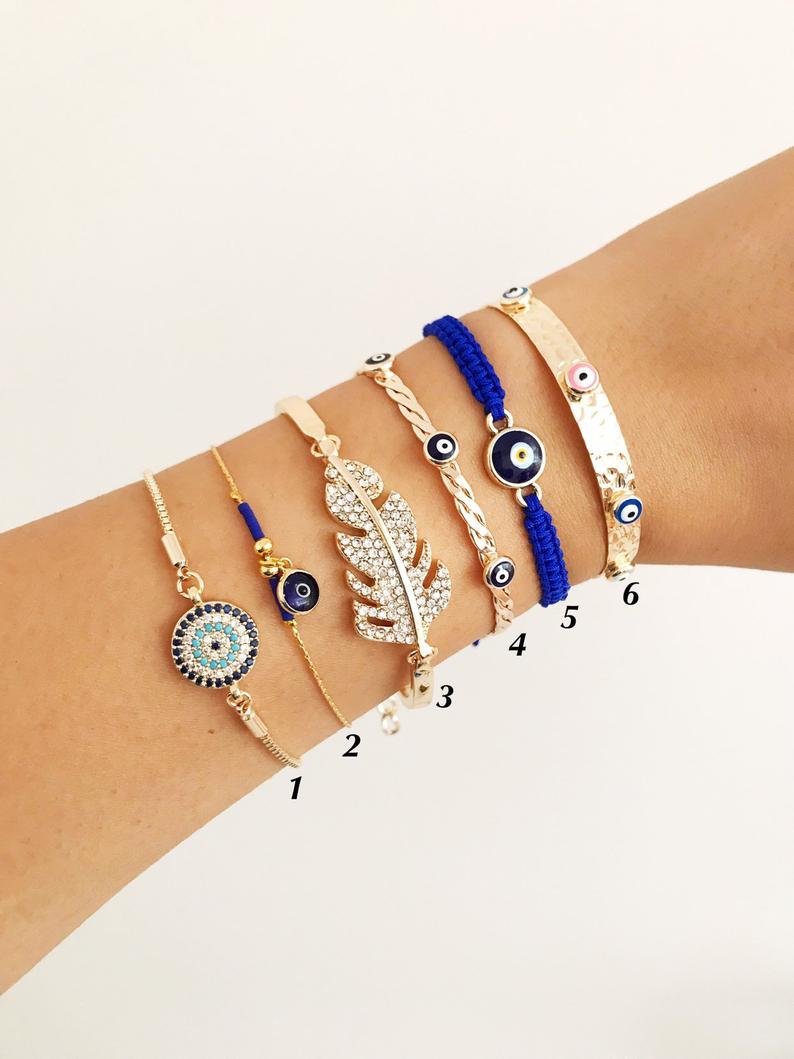 A stylish Greek Evil Eye Bracelet Set featuring a gold bangle and blue evil eye charm, showcasing its handmade craftsmanship and adjustable design.