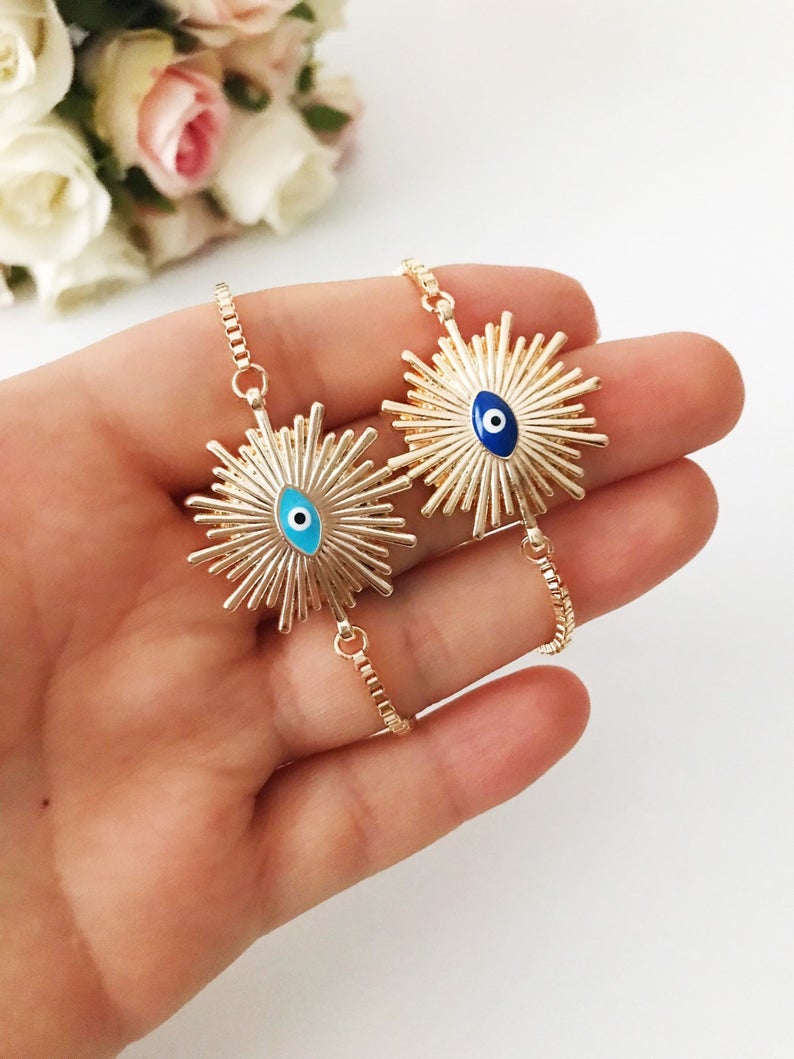 A beautiful Greek Evil Eye Bracelet featuring a sun charm, adjustable gold chain, and a blue evil eye charm, symbolizing protection and good luck.