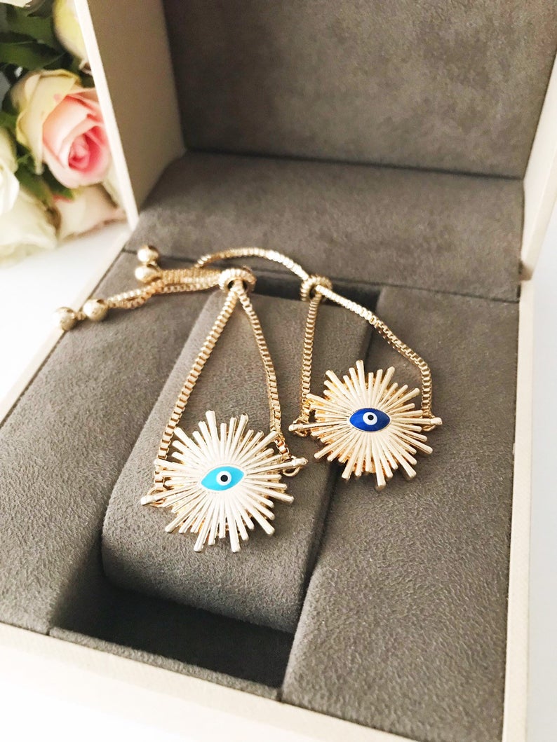 A beautiful Greek Evil Eye Bracelet featuring a sun charm, adjustable gold chain, and a blue evil eye charm, symbolizing protection and good luck.