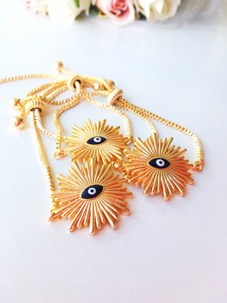A beautiful Greek Evil Eye Bracelet featuring a sun charm, adjustable gold chain, and a blue evil eye charm, symbolizing protection and good luck.