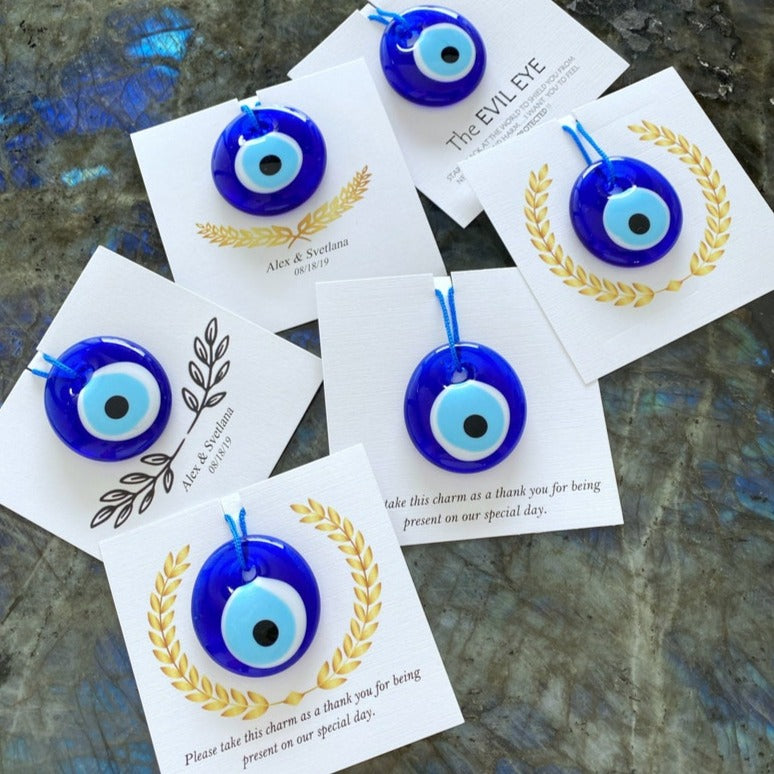 A collection of Greek Evil Eye Wedding Favors featuring blue glass beads and customizable cards, perfect for wedding guests.