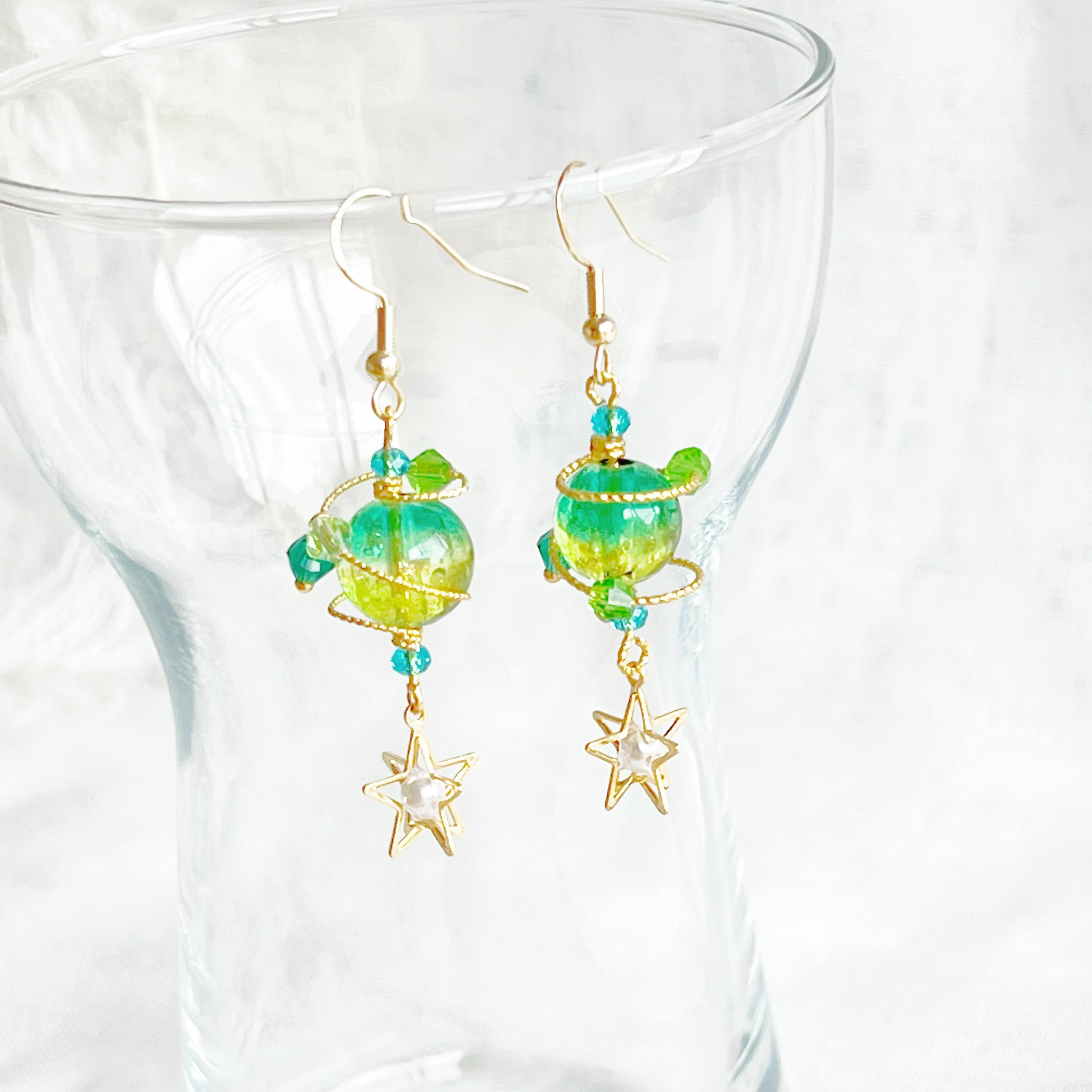 Handmade Green Planet Uranus Earrings featuring a green orb and star drop design, crafted from gold-plated bronze and sterling silver.