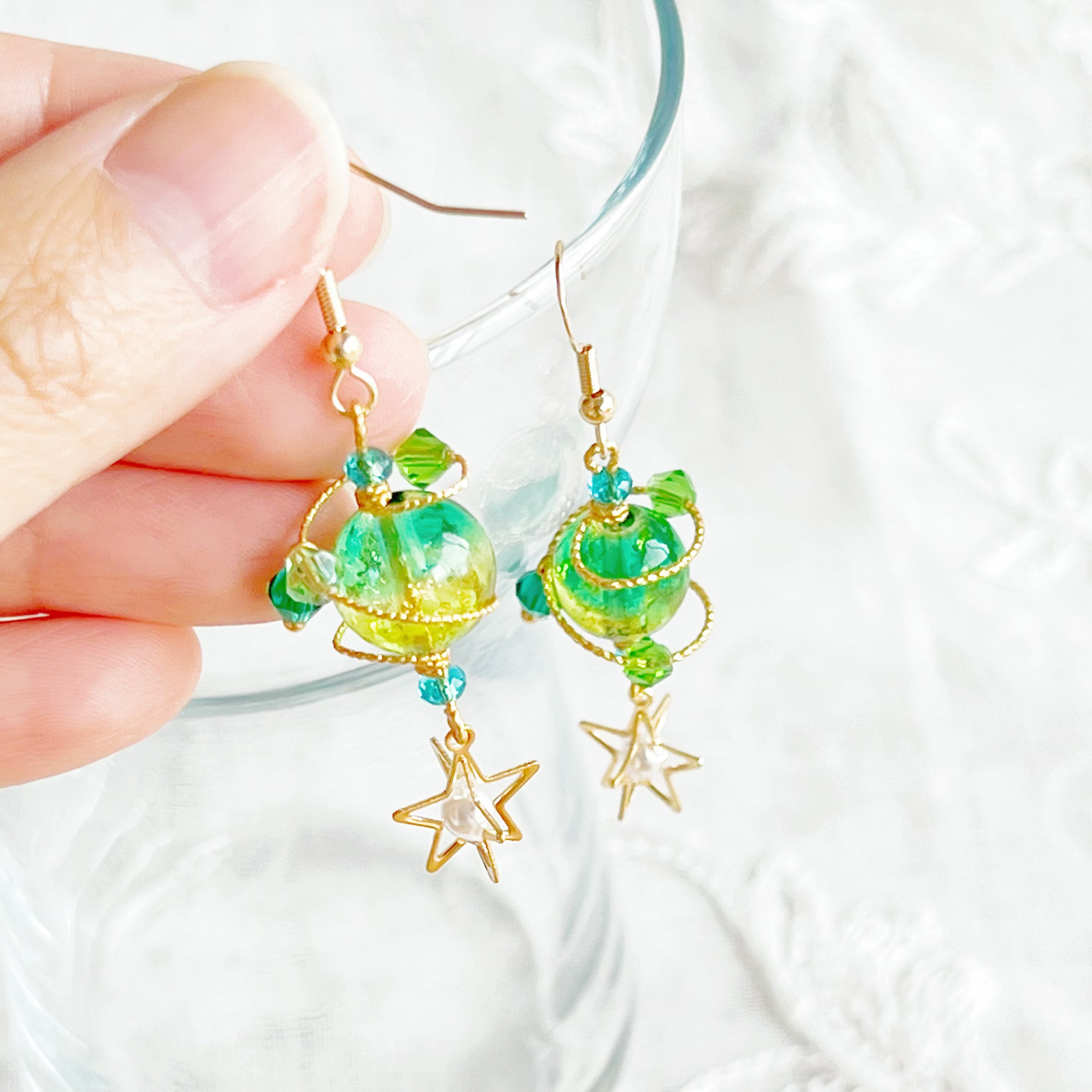 Handmade Green Planet Uranus Earrings featuring a green orb and star drop design, crafted from gold-plated bronze and sterling silver.