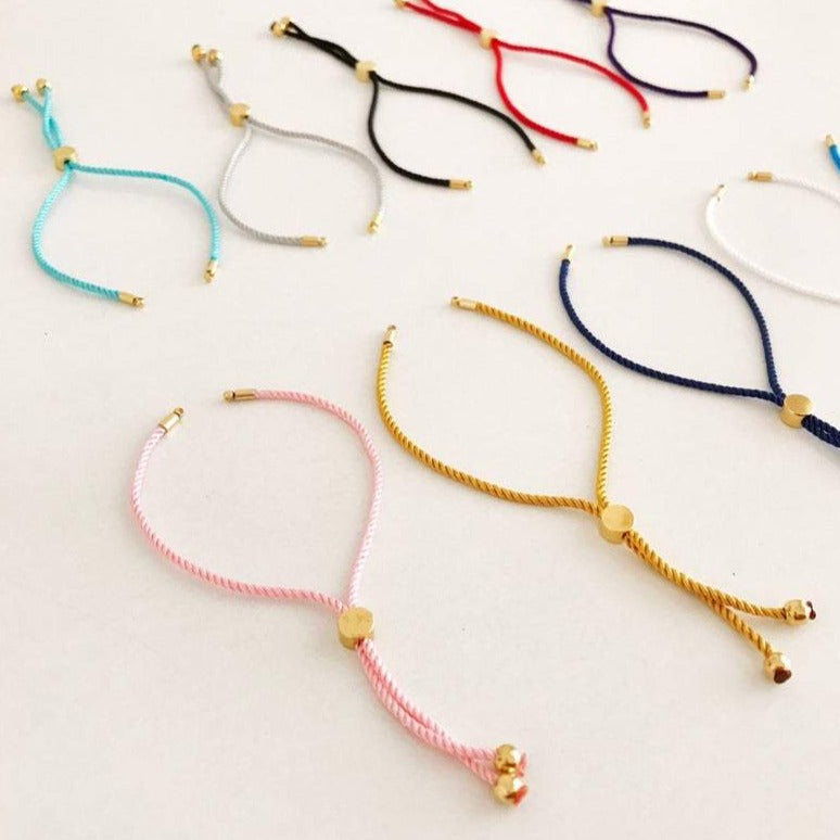 Half-finished cord bracelet in various colors with adjustable slider stopper beads, perfect for DIY jewelry making.