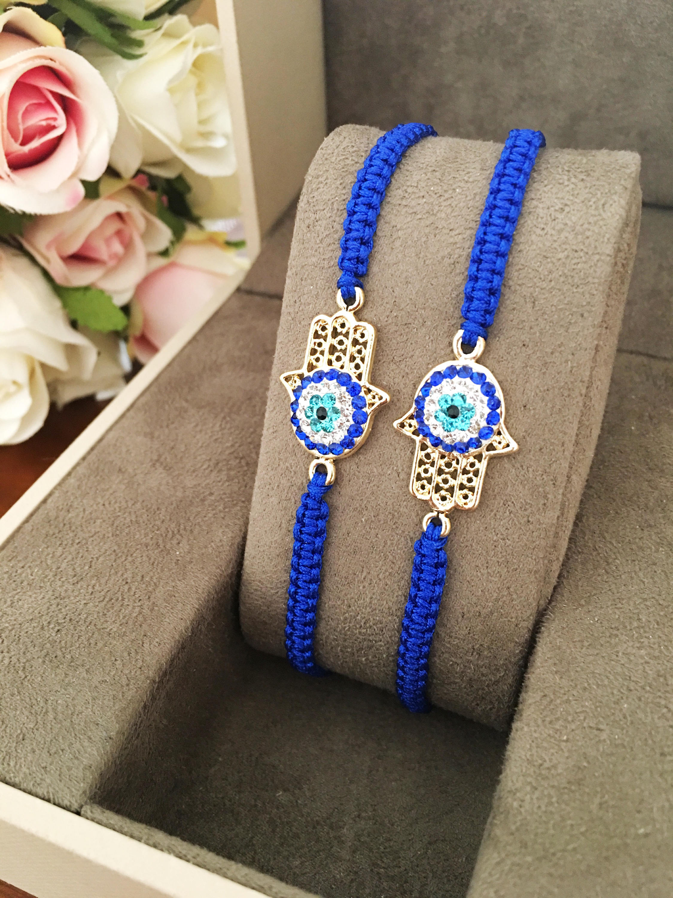 Handmade Hamsa bracelet featuring a gold-plated evil eye charm on dark blue macramé string, adjustable for all wrist sizes.