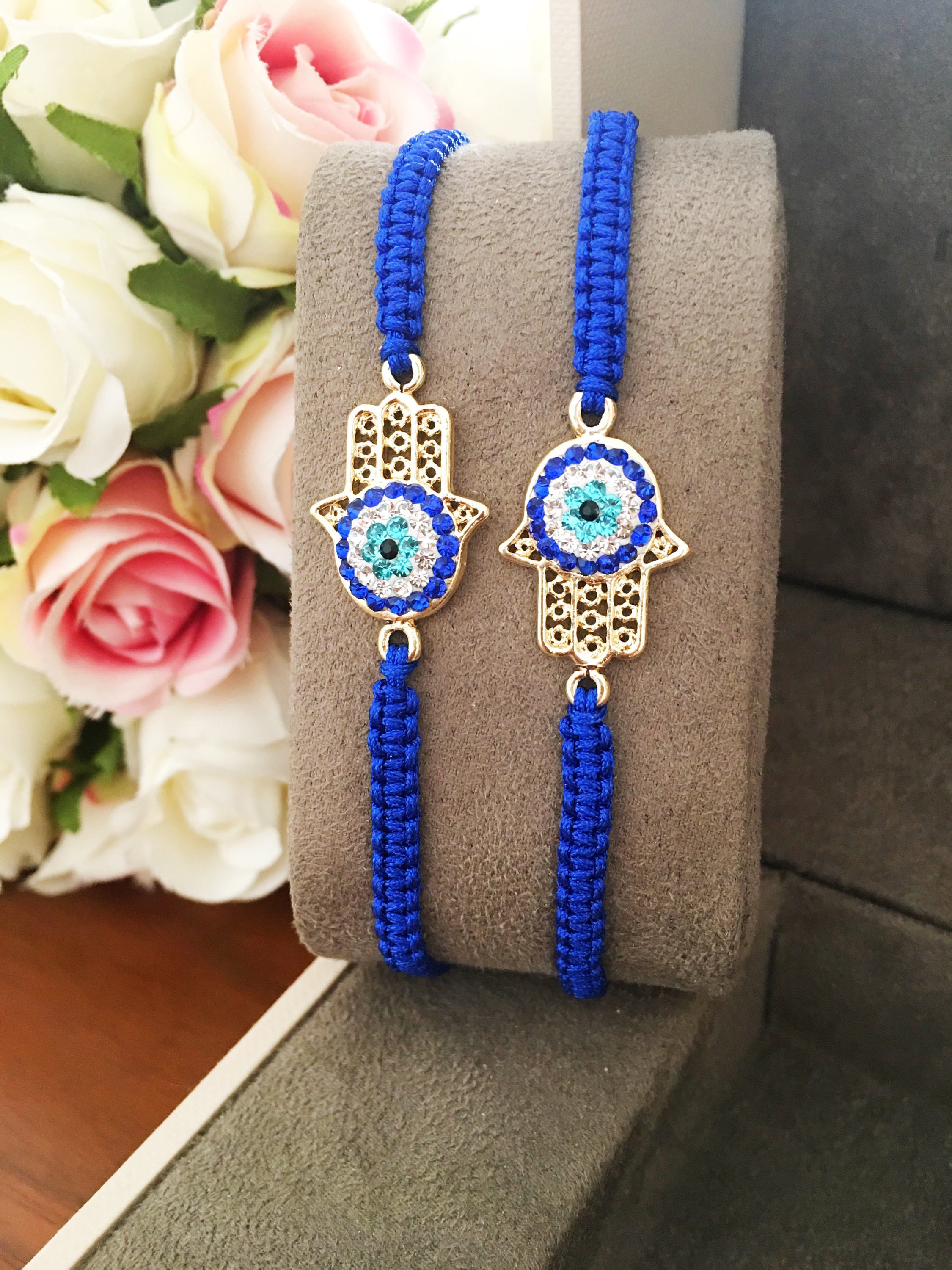 Handmade Hamsa bracelet featuring a gold-plated evil eye charm on dark blue macramé string, adjustable for all wrist sizes.