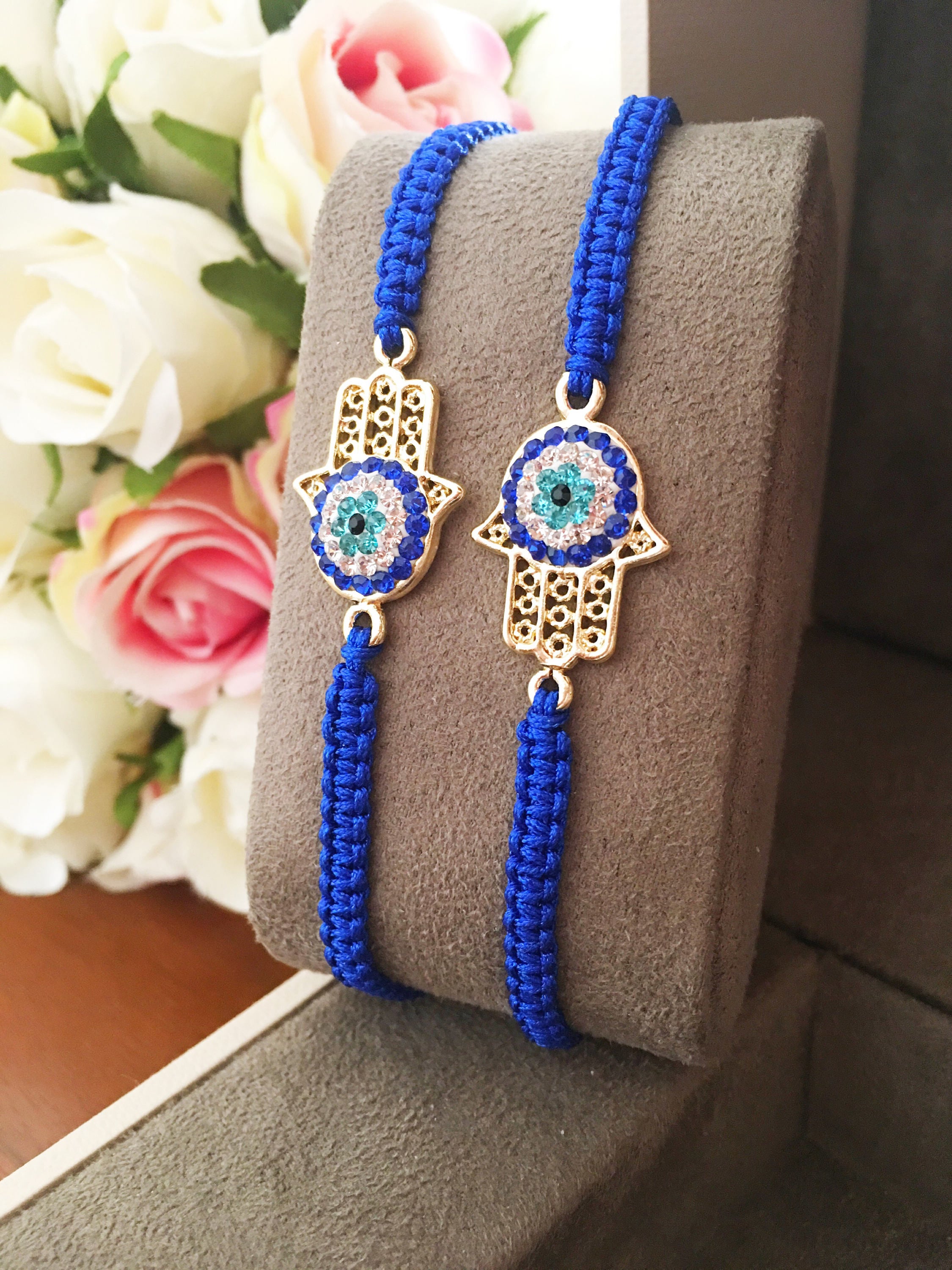Handmade Hamsa bracelet featuring a gold-plated evil eye charm on dark blue macramé string, adjustable for all wrist sizes.