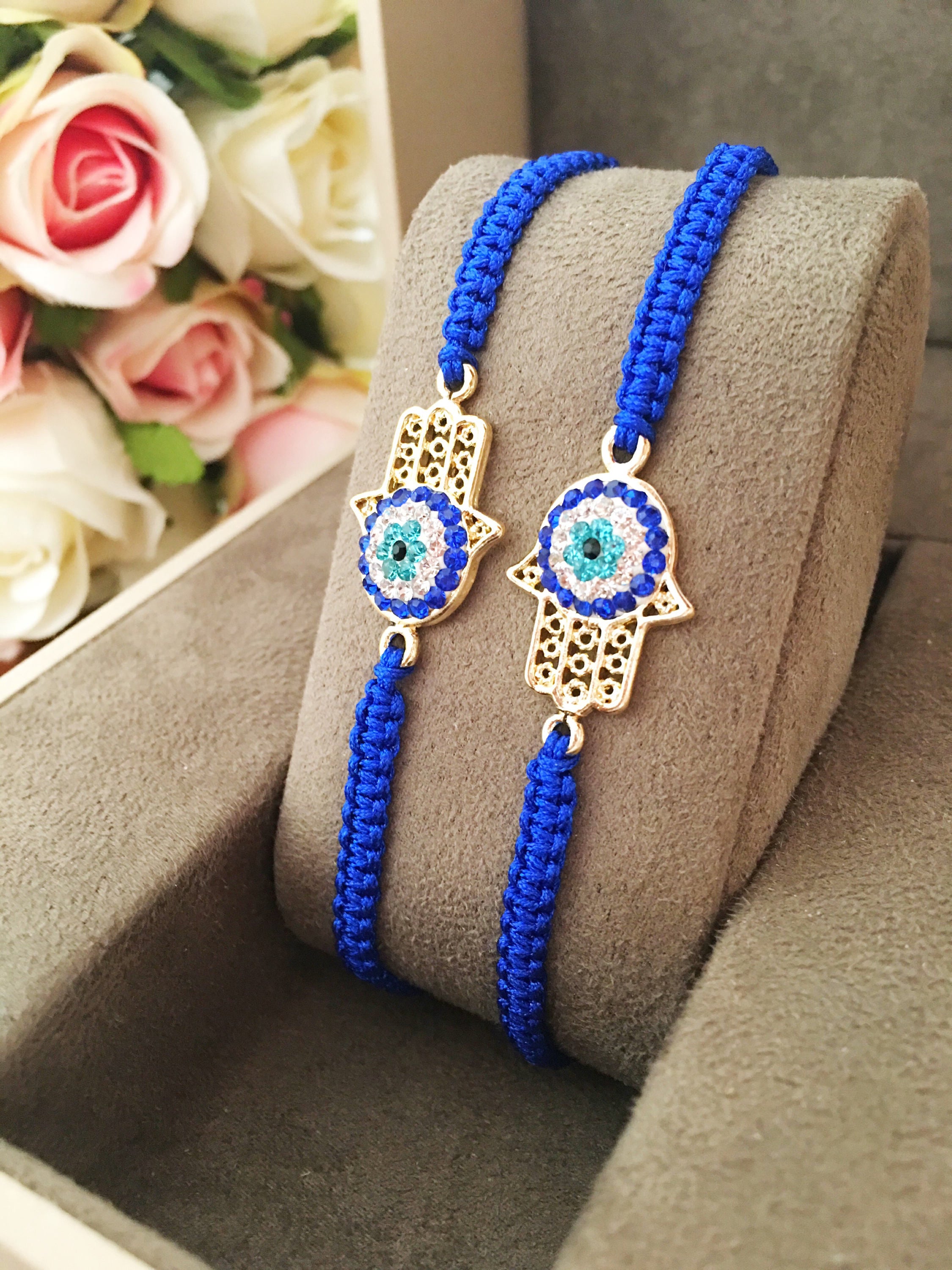 Handmade Hamsa bracelet featuring a gold-plated evil eye charm on dark blue macramé string, adjustable for all wrist sizes.