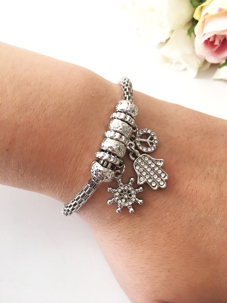 Hamsa Charm Bracelet featuring zirconia stones, available in rose gold, gold, and silver, showcasing adjustable design and 7 unique charms.