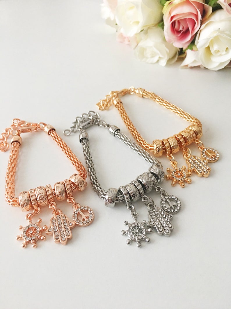 Hamsa Charm Bracelet featuring zirconia stones, available in rose gold, gold, and silver, showcasing adjustable design and 7 unique charms.