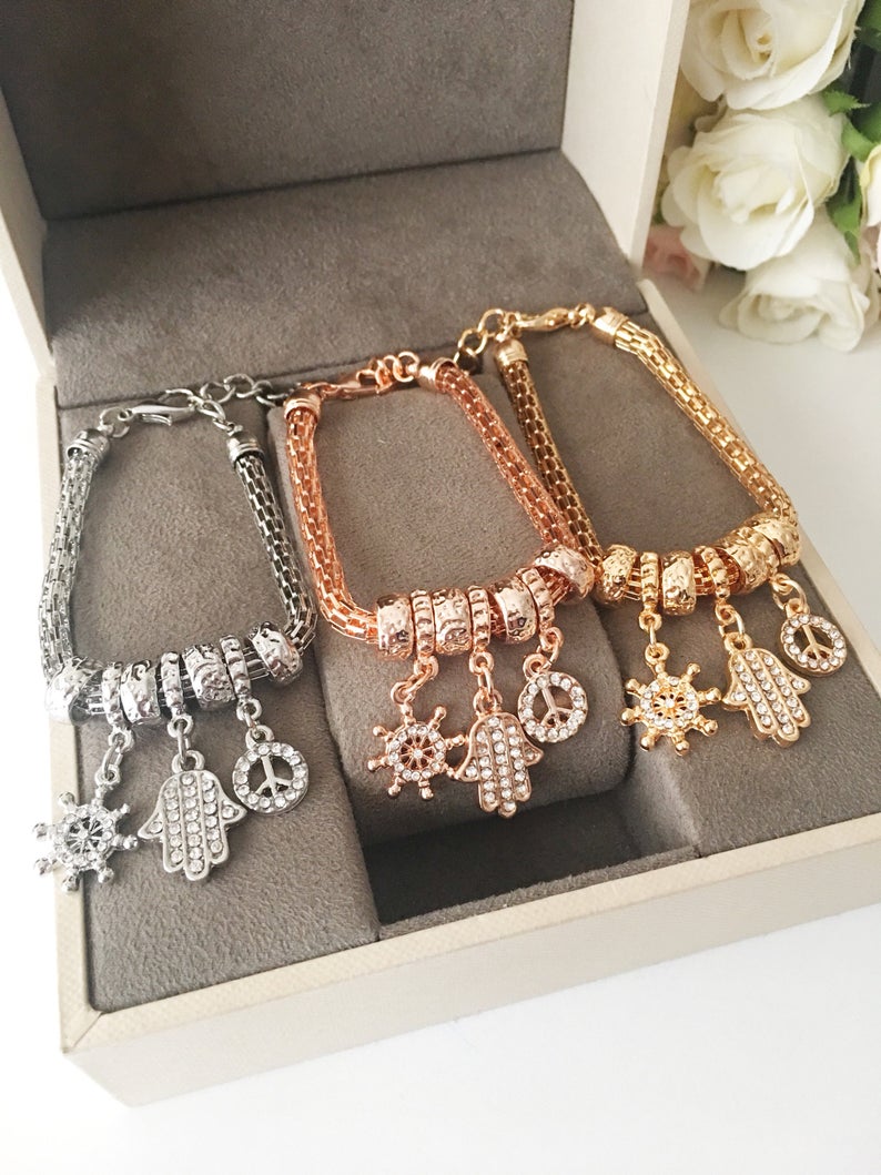 Hamsa Charm Bracelet featuring zirconia stones, available in rose gold, gold, and silver, showcasing adjustable design and 7 unique charms.