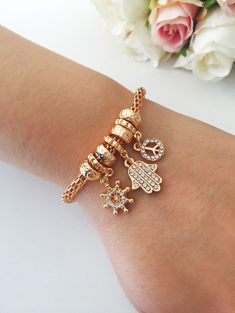 Hamsa Charm Bracelet featuring zirconia stones, available in rose gold, gold, and silver, showcasing adjustable design and 7 unique charms.