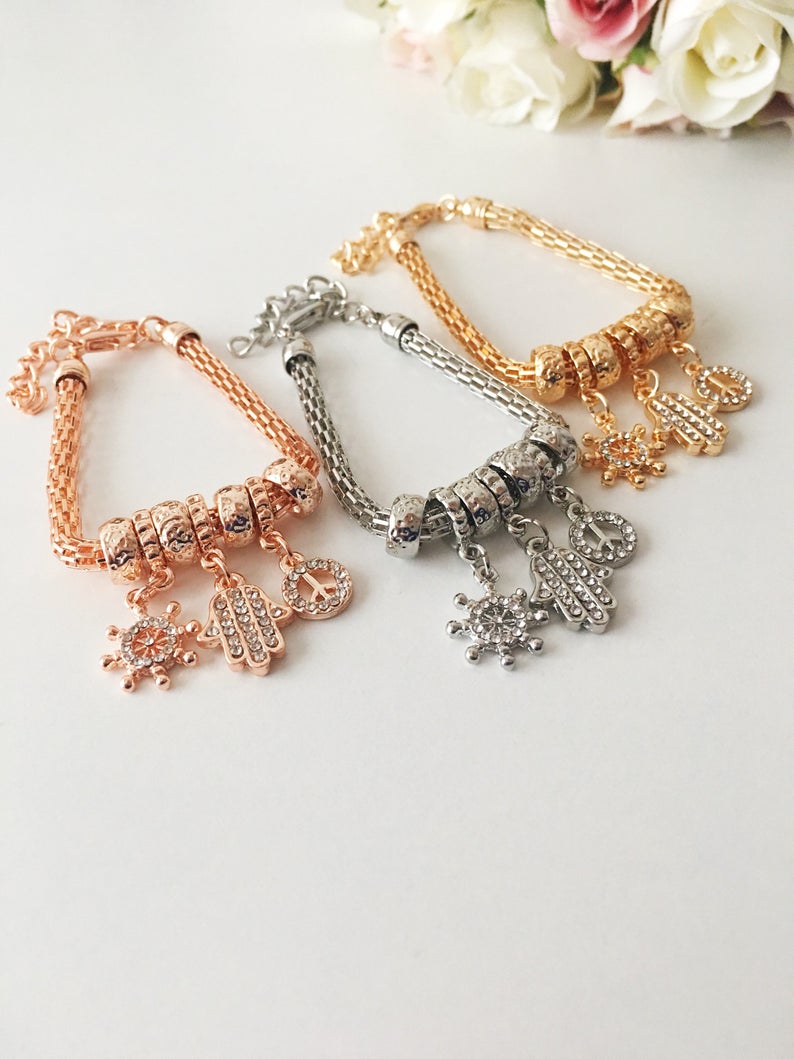 Hamsa Charm Bracelet featuring zirconia stones, available in rose gold, gold, and silver, showcasing adjustable design and 7 unique charms.