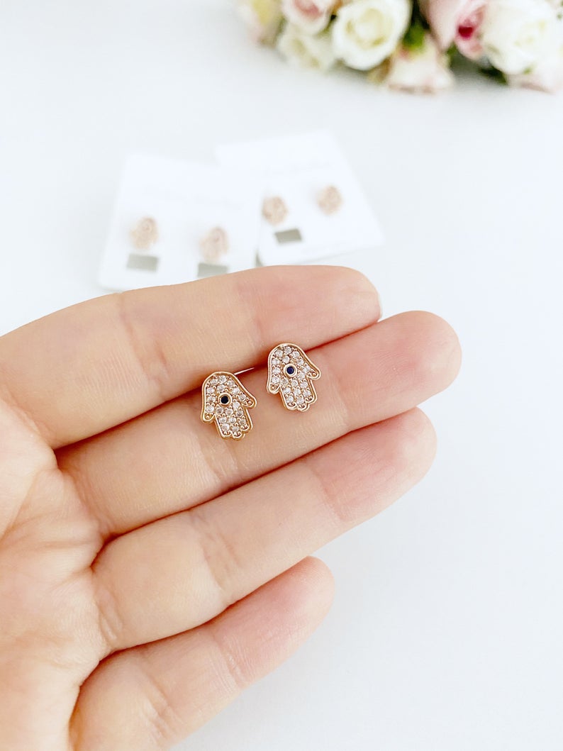 A pair of handmade Hamsa earrings featuring zircon stones, available in silver and rose gold, symbolizing protection and good luck.