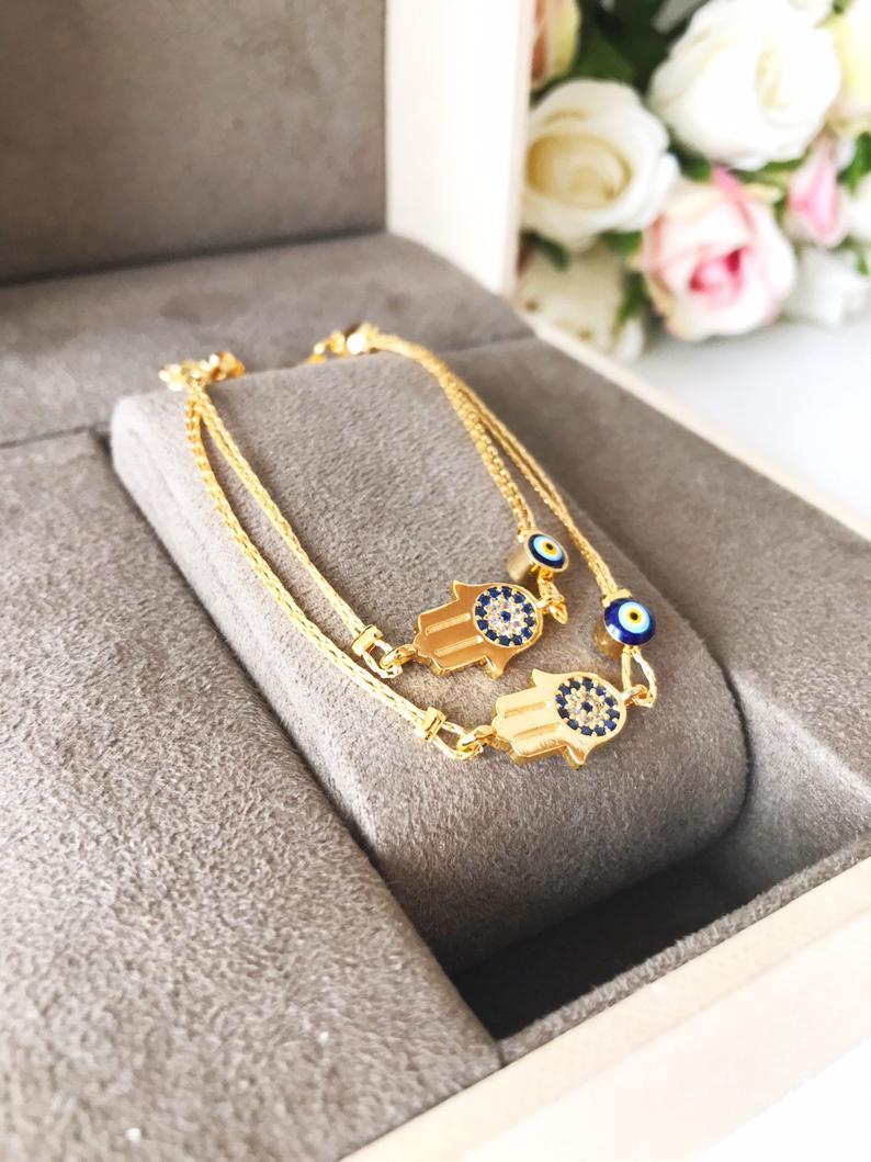 A beautiful handmade Hamsa Evil Eye Bracelet featuring a gold chain, hamsa charm, and evil eye beads, symbolizing protection and good fortune.