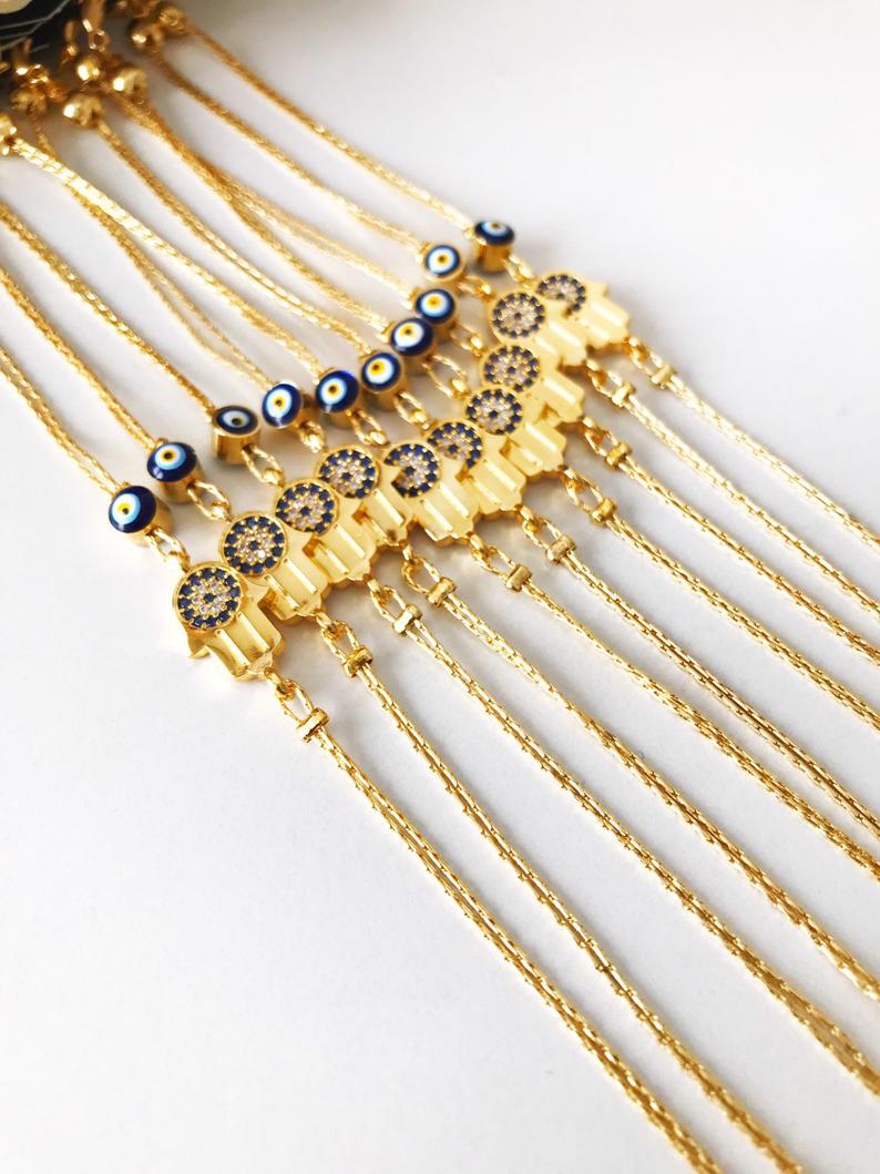 A beautiful handmade Hamsa Evil Eye Bracelet featuring a gold chain, hamsa charm, and evil eye beads, symbolizing protection and good fortune.