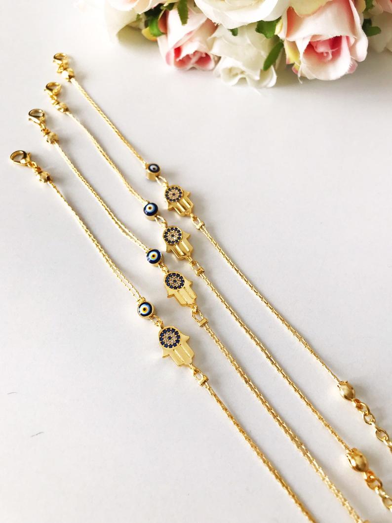 A beautiful handmade Hamsa Evil Eye Bracelet featuring a gold chain, hamsa charm, and evil eye beads, symbolizing protection and good fortune.