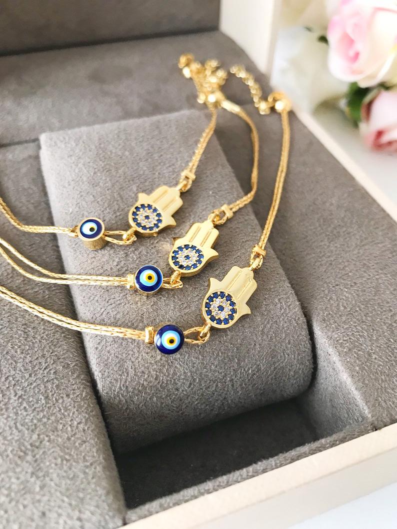 A beautiful handmade Hamsa Evil Eye Bracelet featuring a gold chain, hamsa charm, and evil eye beads, symbolizing protection and good fortune.